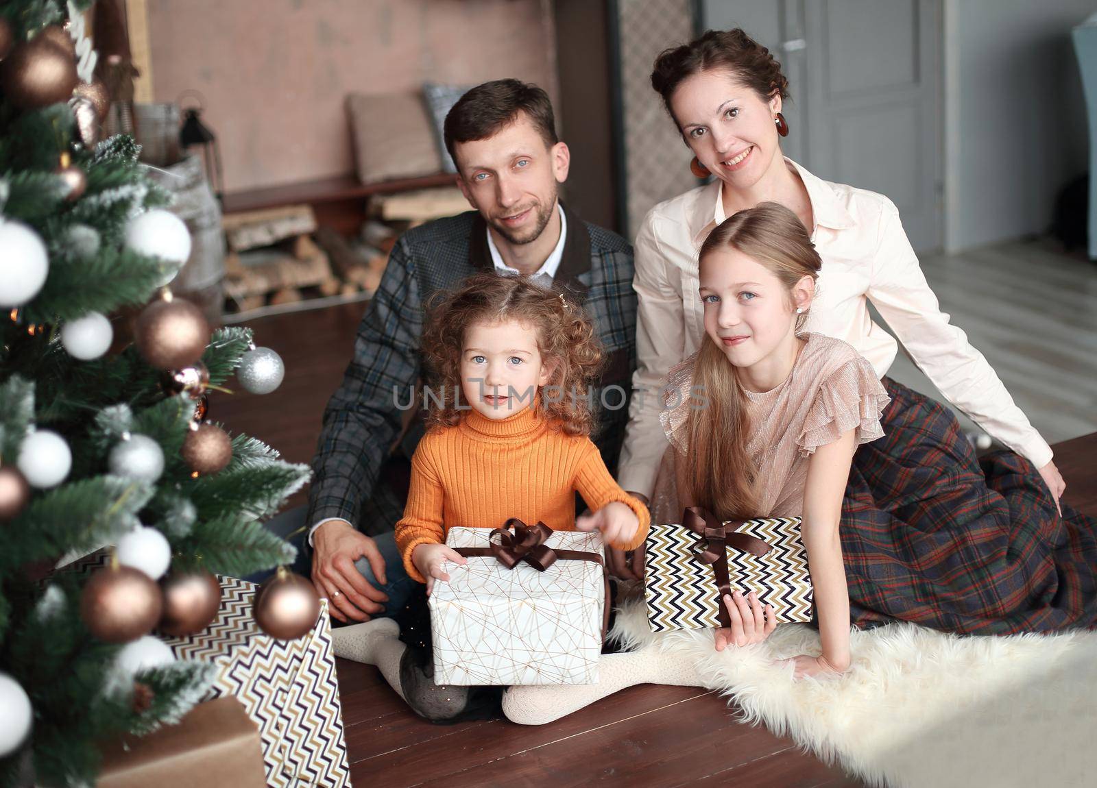 happy family sitting near Christmas tree on Christmas evening. holiday concept