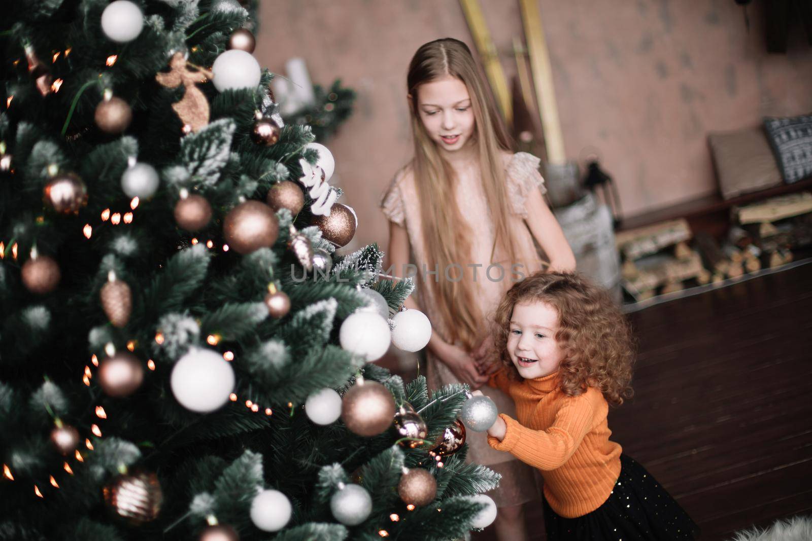 close up.two pretty sisters standing by the Christmas tree by SmartPhotoLab