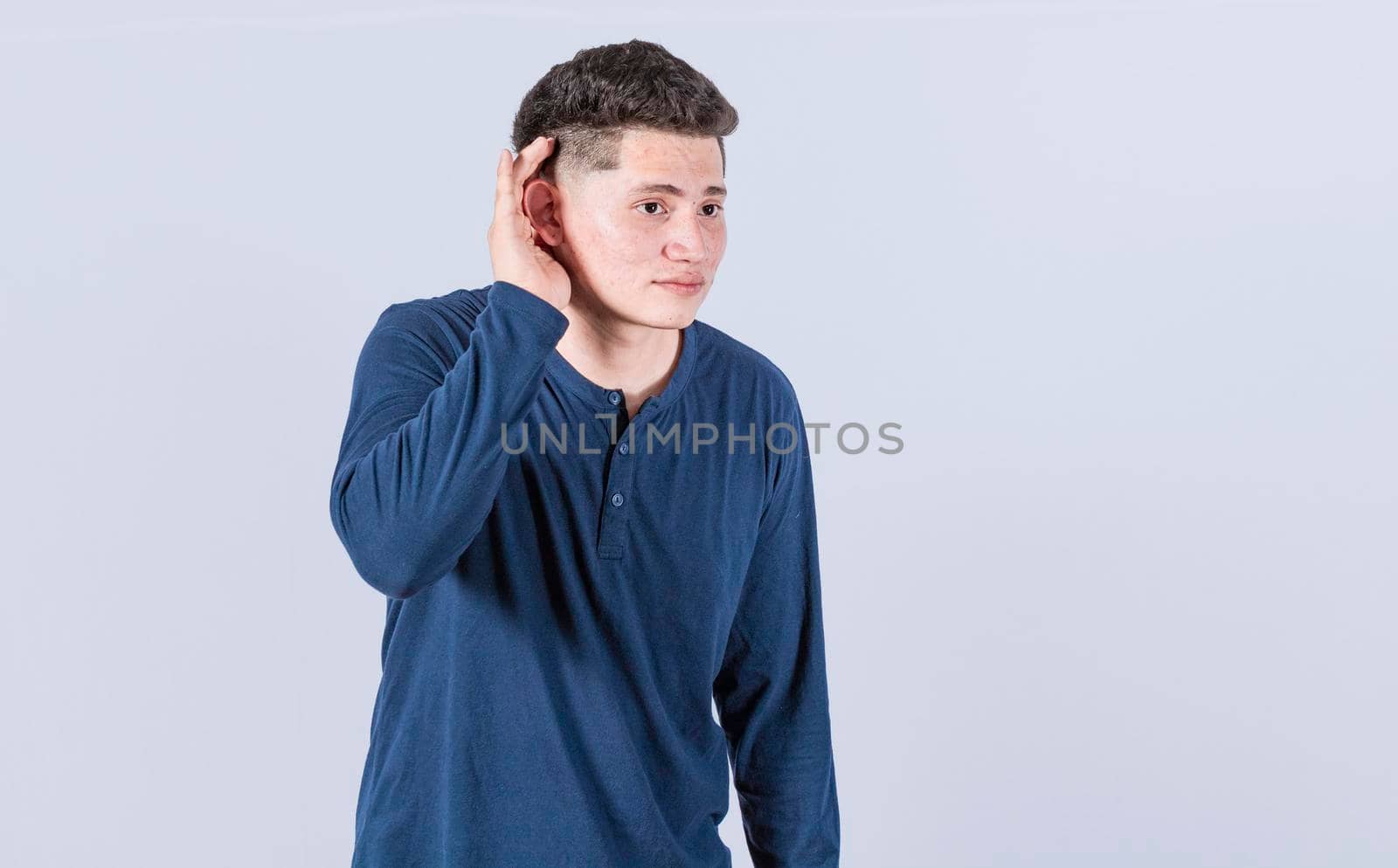 Man with hand to his ear listening to something, young man tilting his ear to listen, Man listening putting hand to ear