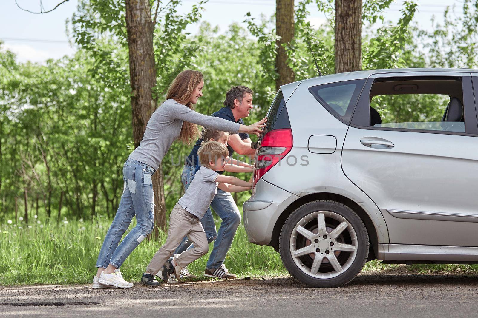 family with children pushing a faulty car by SmartPhotoLab