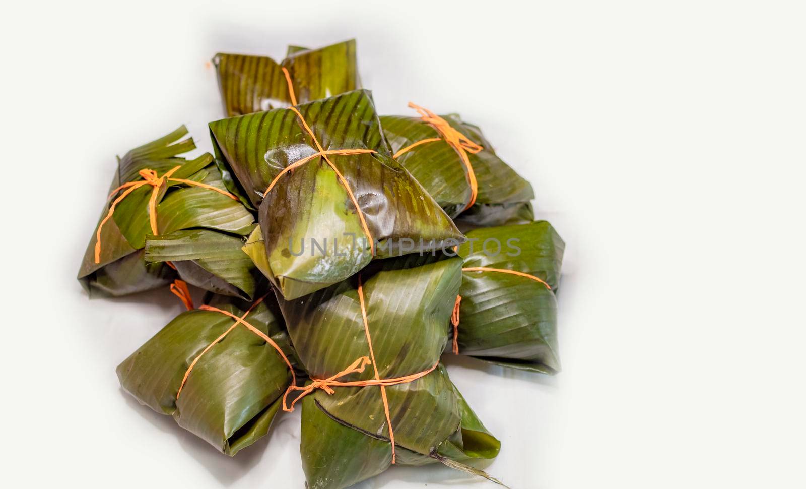 Close up of nacatamales with banana leaves on white background, Nacatamales heaped on white background by isaiphoto