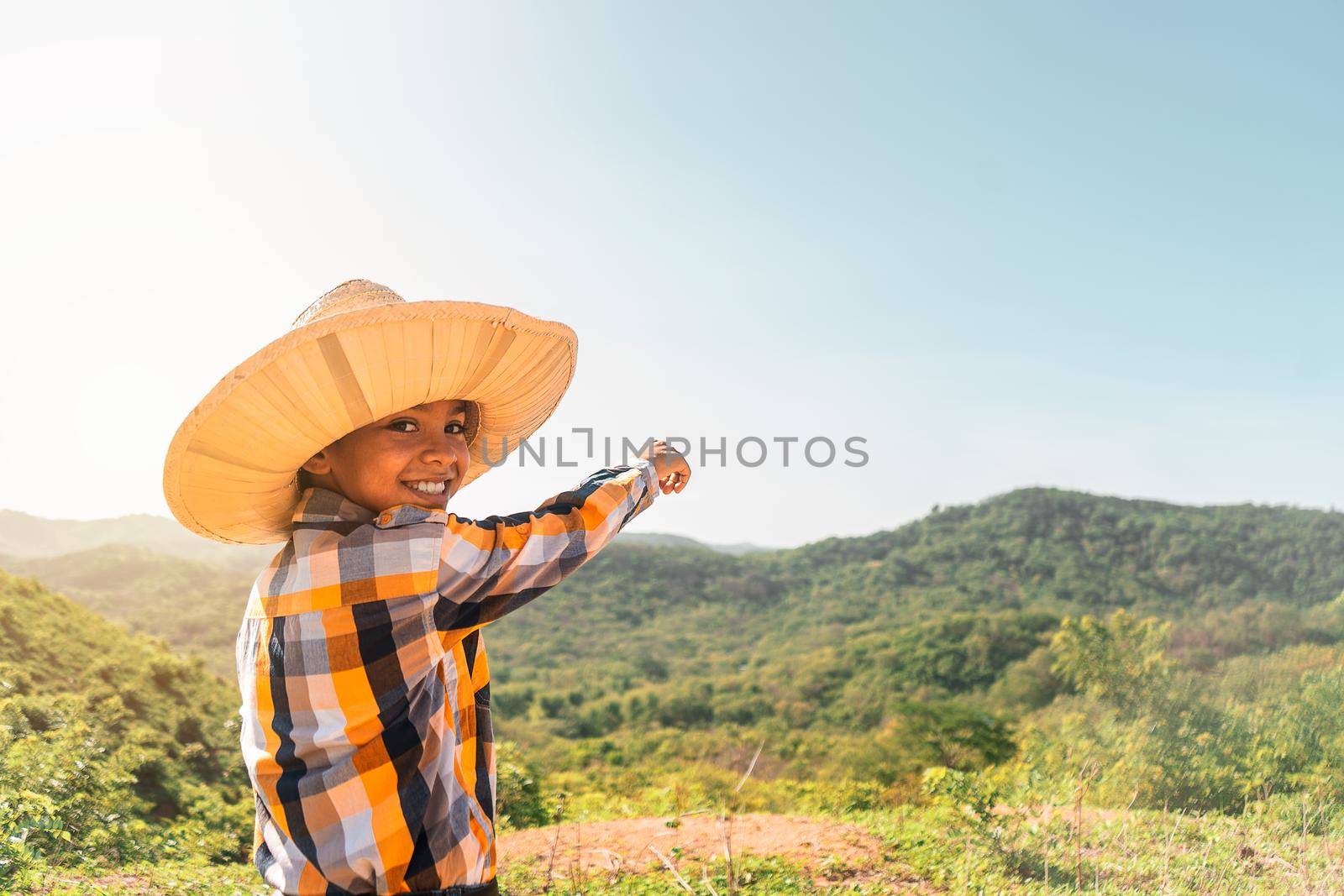 Latin boy with traditional country clothes in Latin America and hat looking at camera and smiling and pointing to the horizon in a mountainous area of Rivas Nicaragua.