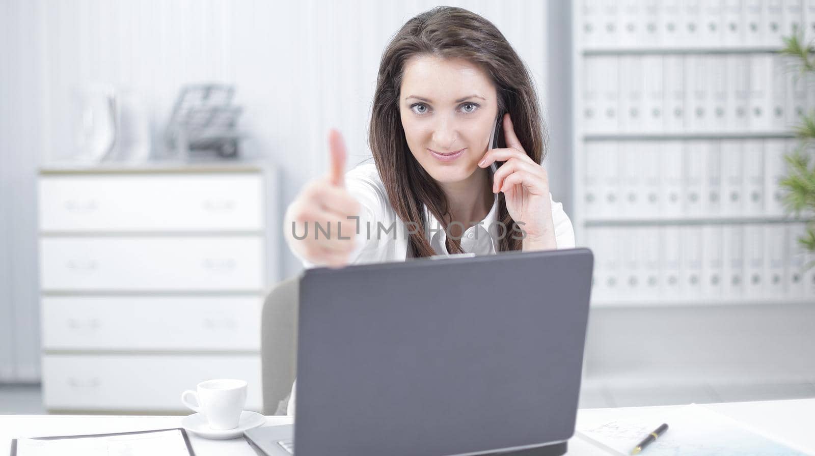 successful business woman showing thumb up in the workplace by SmartPhotoLab