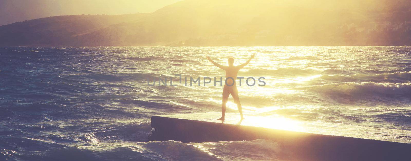 Feeling of freedom concept. Man standing on pier facing to the sea with big waves.