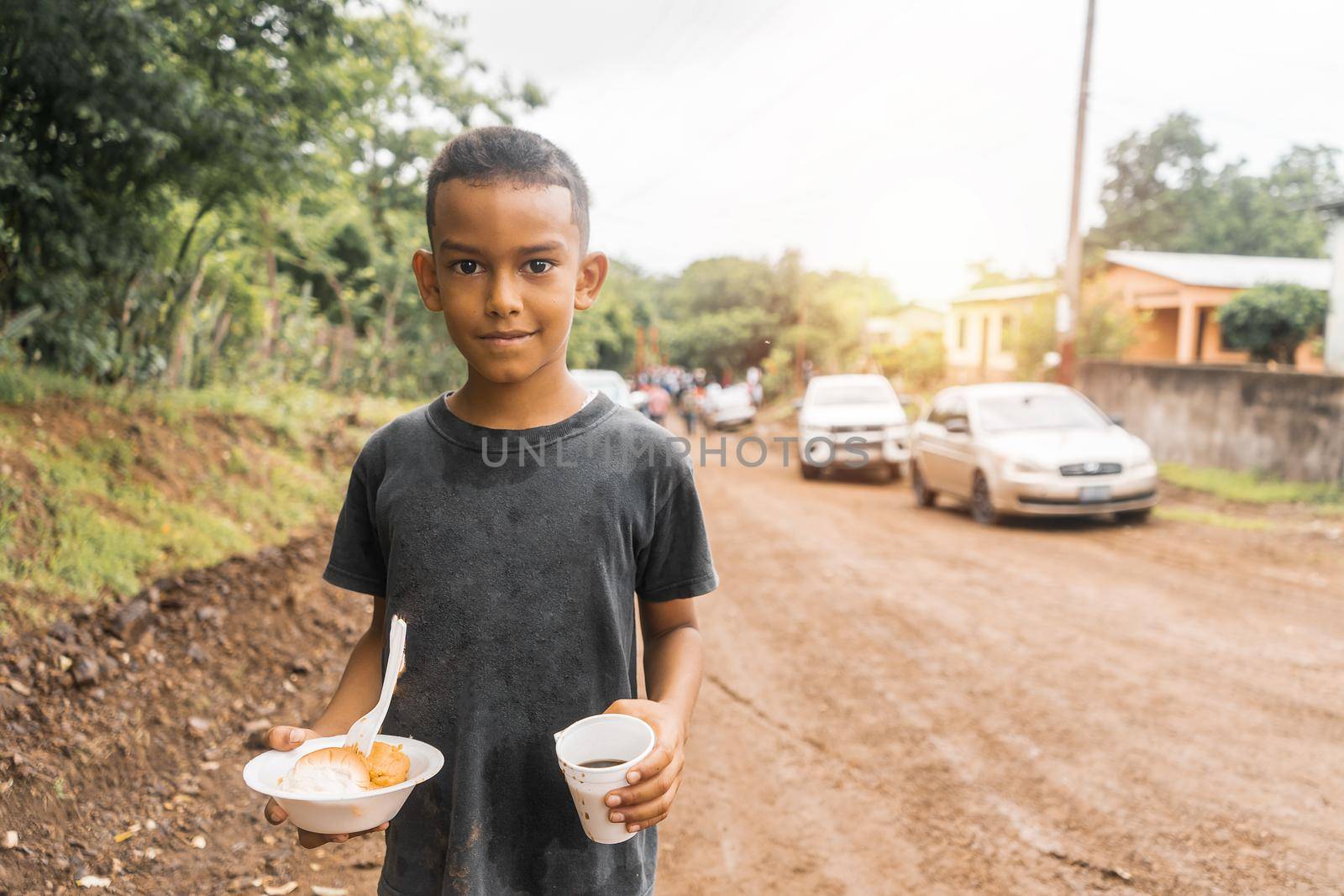 Nicaraguan boy holding a plate with nacatamal and a glass with coffee during a local celebration by cfalvarez