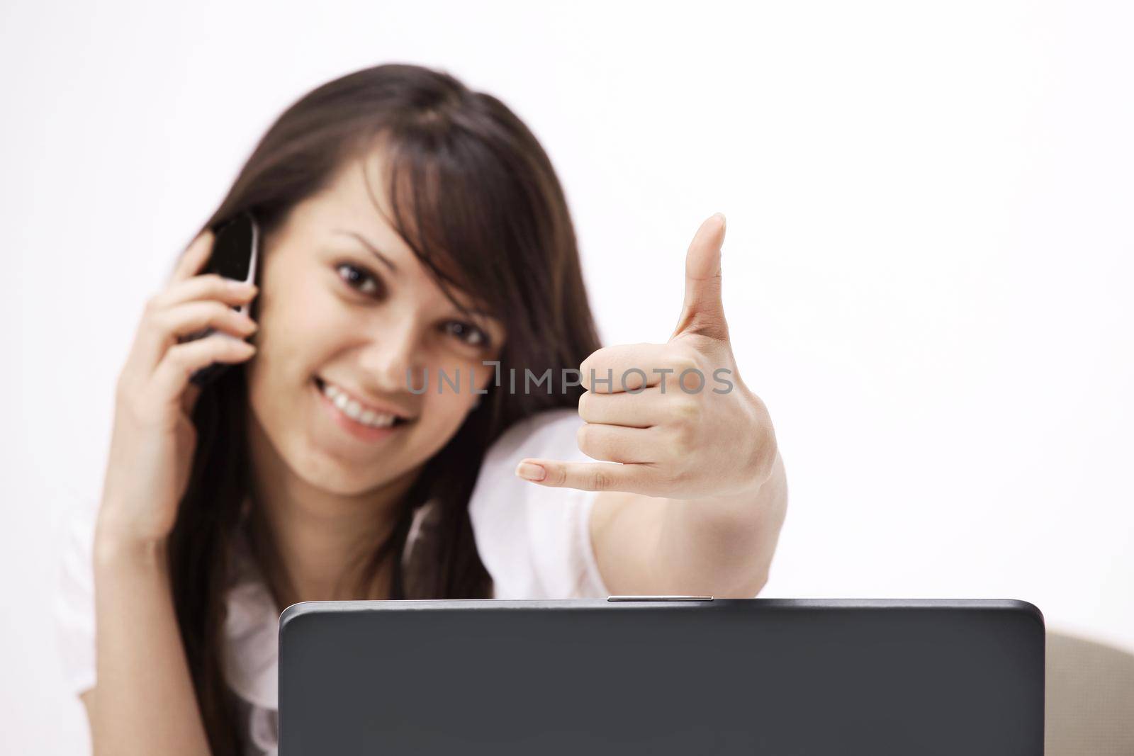smiling young woman sitting behind a Desk and showing thumb up. by SmartPhotoLab