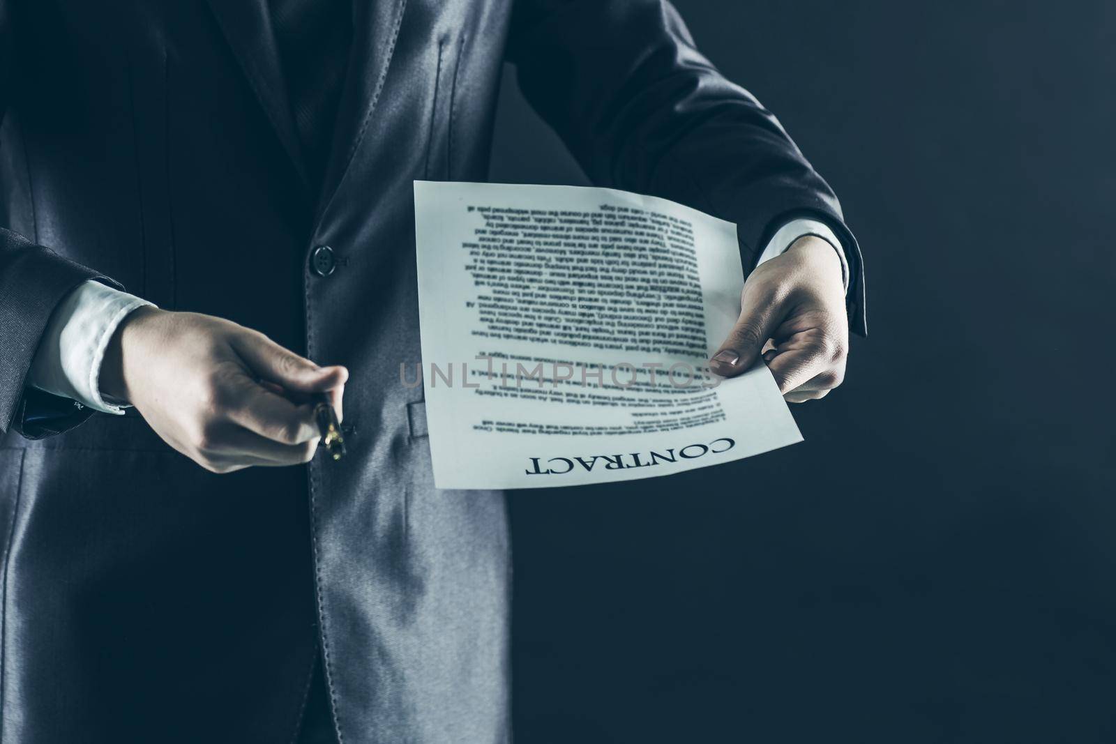 closeup of a businessman holding a pen and a document with the terms of the contract. by SmartPhotoLab