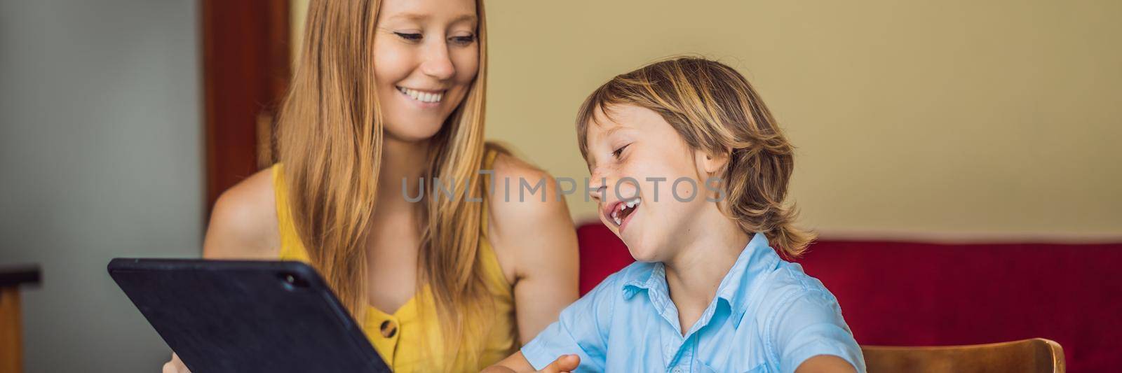 A boy studying online at home using a tablet. Mom helps him learn. Studying during quarantine. Global pandemic covid19 virus BANNER, LONG FORMAT by galitskaya