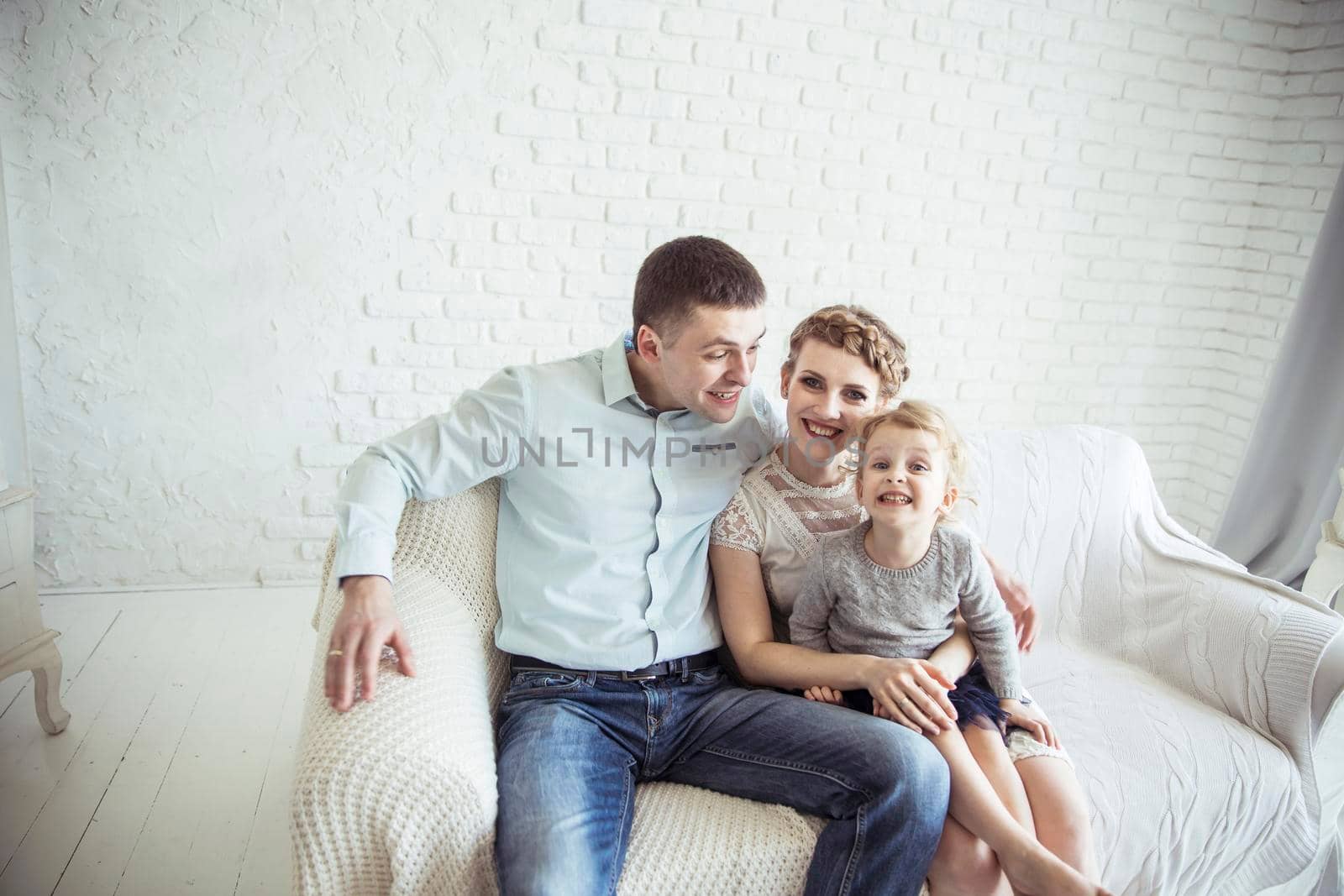 portrait of happy family sitting on sofa in living room by SmartPhotoLab