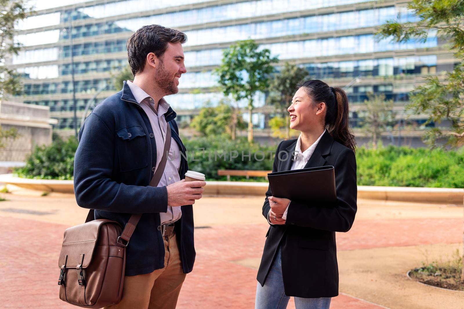 coworkers chatting happily in the park in front of the office building, concept of work and business lifestyle