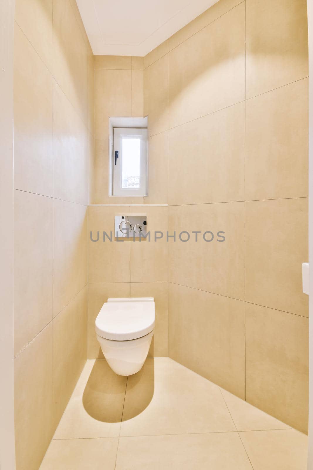 Interior of narrow restroom with sink and wall hung toilet with white walls and checkered floor