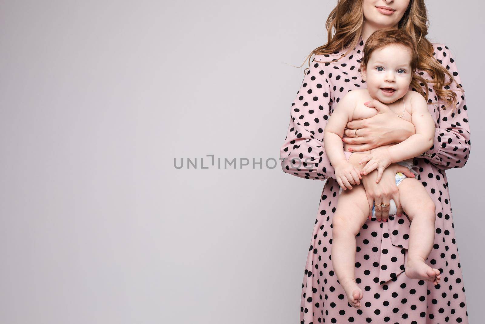 A beautiful family with a small child in the studio on a gray background. by StudioLucky