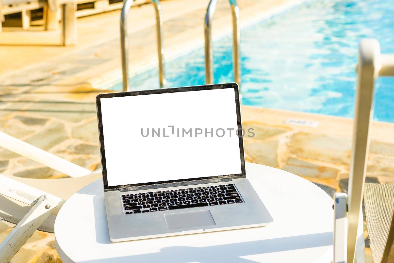 A laptop with an empty screen stands in the courtyard of a beautiful home garden, in Sunny weather