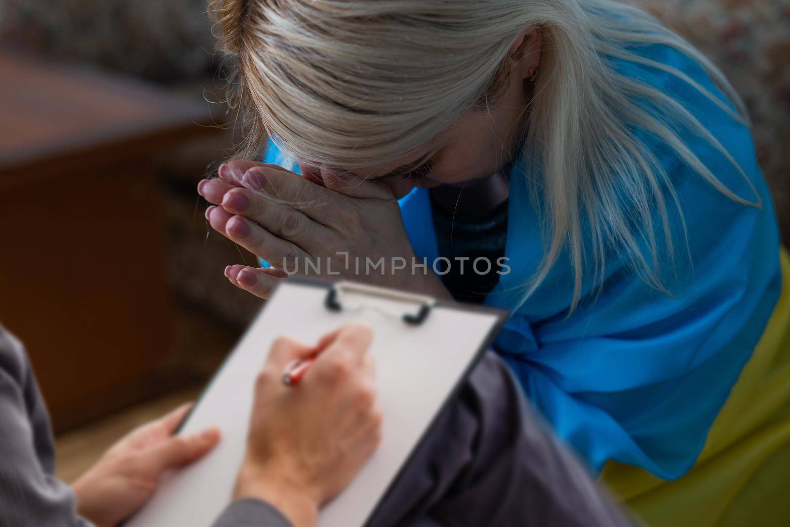 A young beautiful ukraine woman is crying while sitting with psychologist.