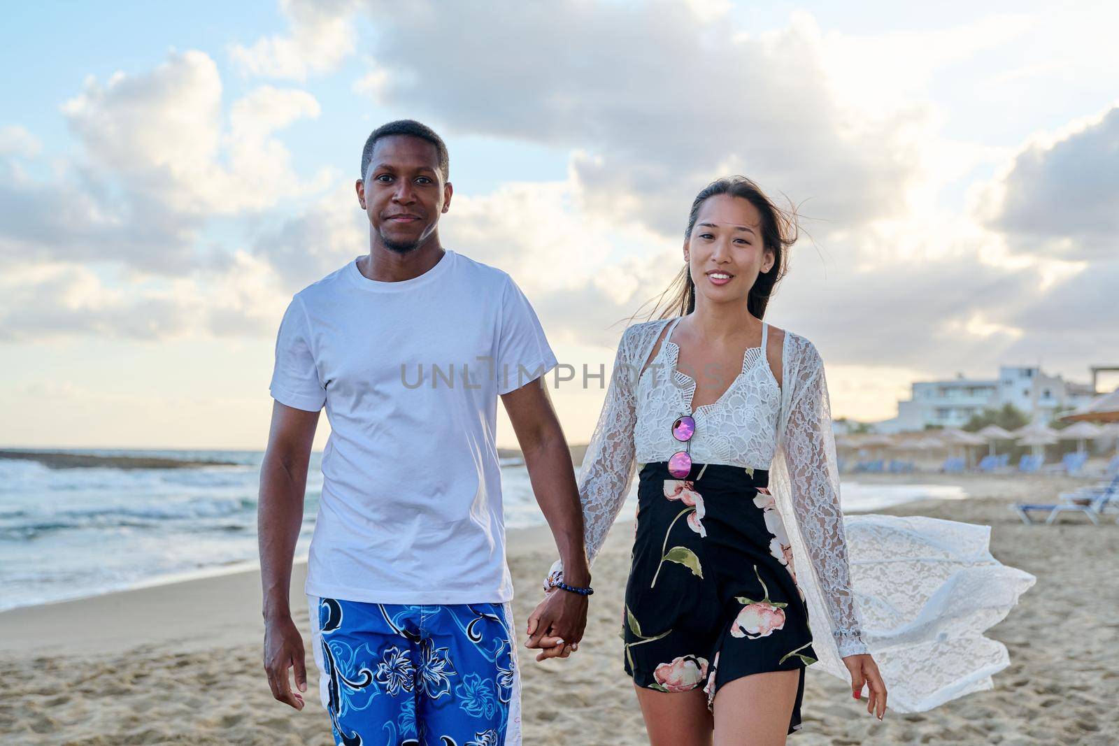 Young happy couple walking on the beach holding hands. by VH-studio