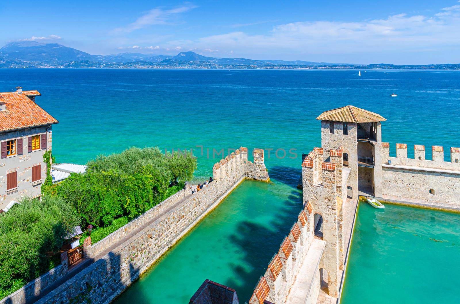 Small fortified harbor with turquoise water, Scaligero Castle Castello fortress in Sirmione by Aliaksandr_Antanovich
