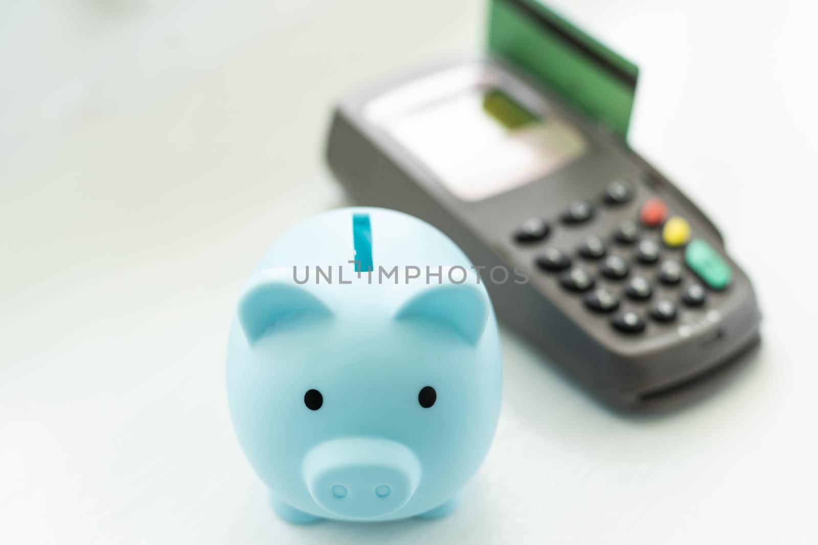 money and savings coins with dollar bills and a payment terminal for cashless payments with a pink piggy bank for savings