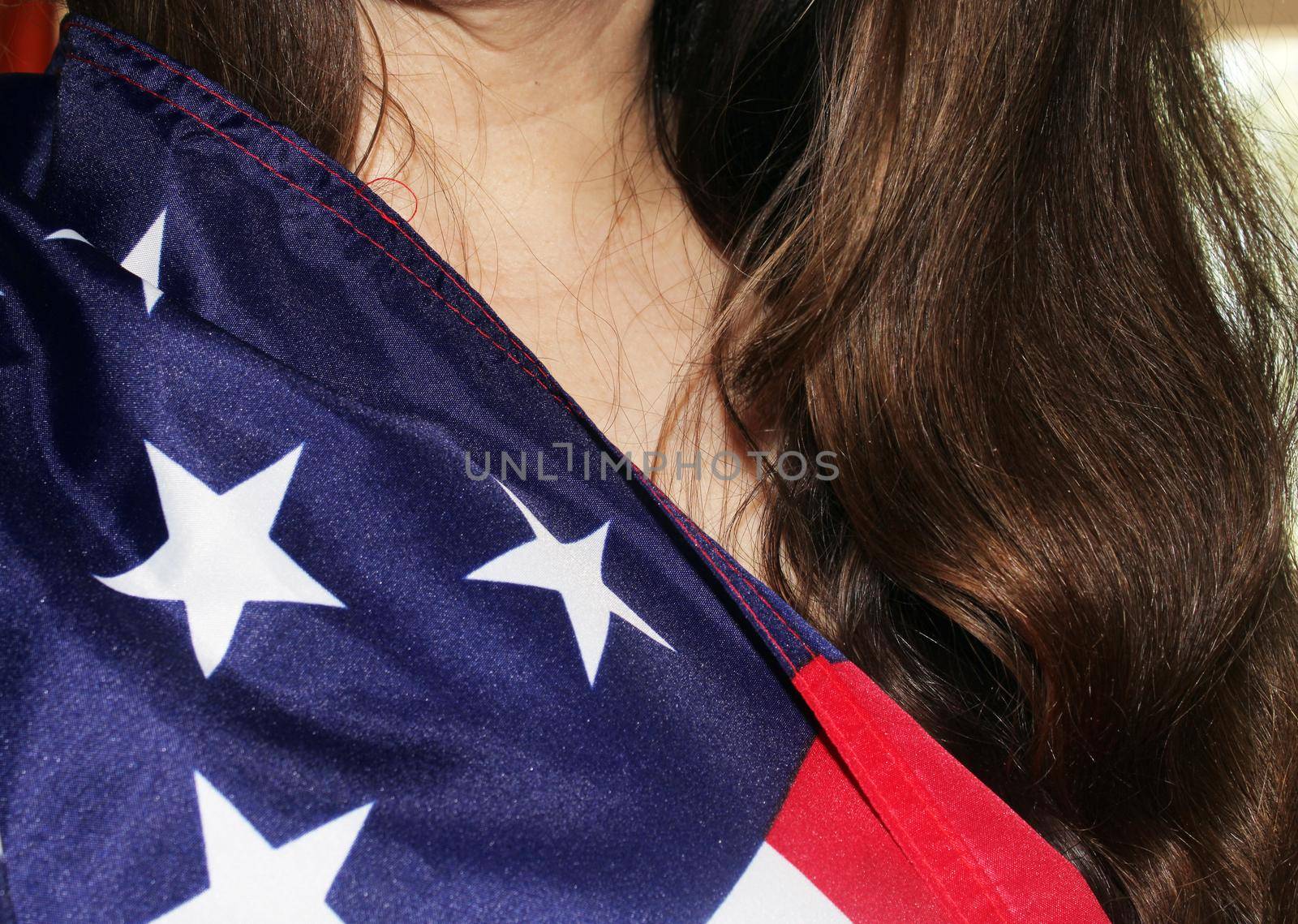 A girl with long dark hair holds a US flag in her hands. High quality photo