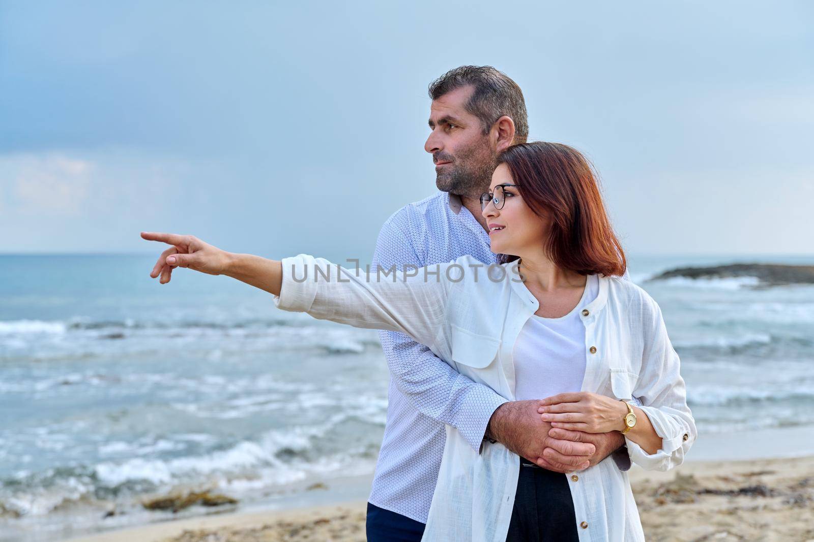 Outdoor portrait of mature couple hugging on beach, background of sea nature, copy space. Middle-aged happy romantic man and woman. Relationships, feelings, lifestyle, marriage, family, people concept