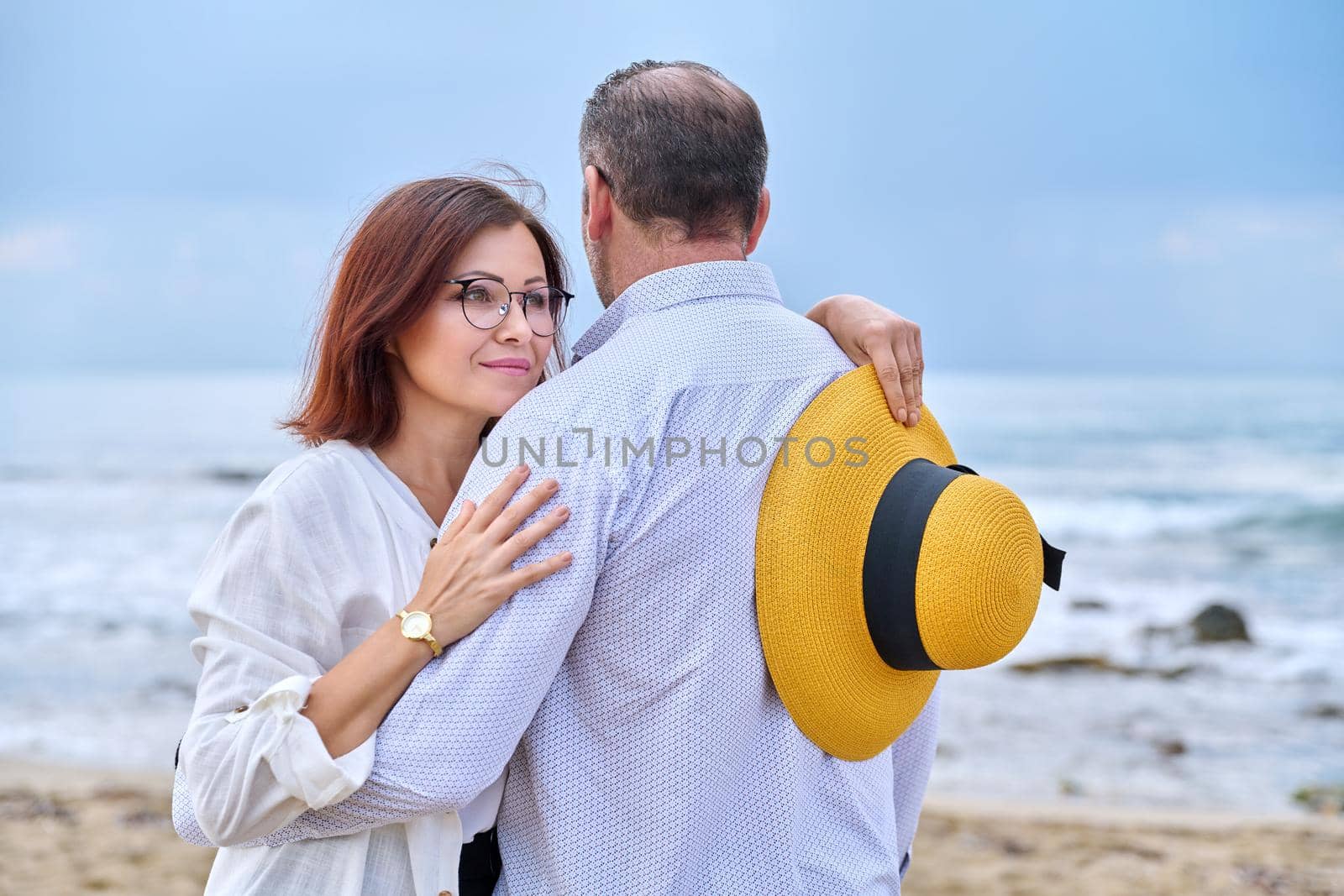 Portrait of happy hugging middle age couple, sea nature sky waves background. by VH-studio