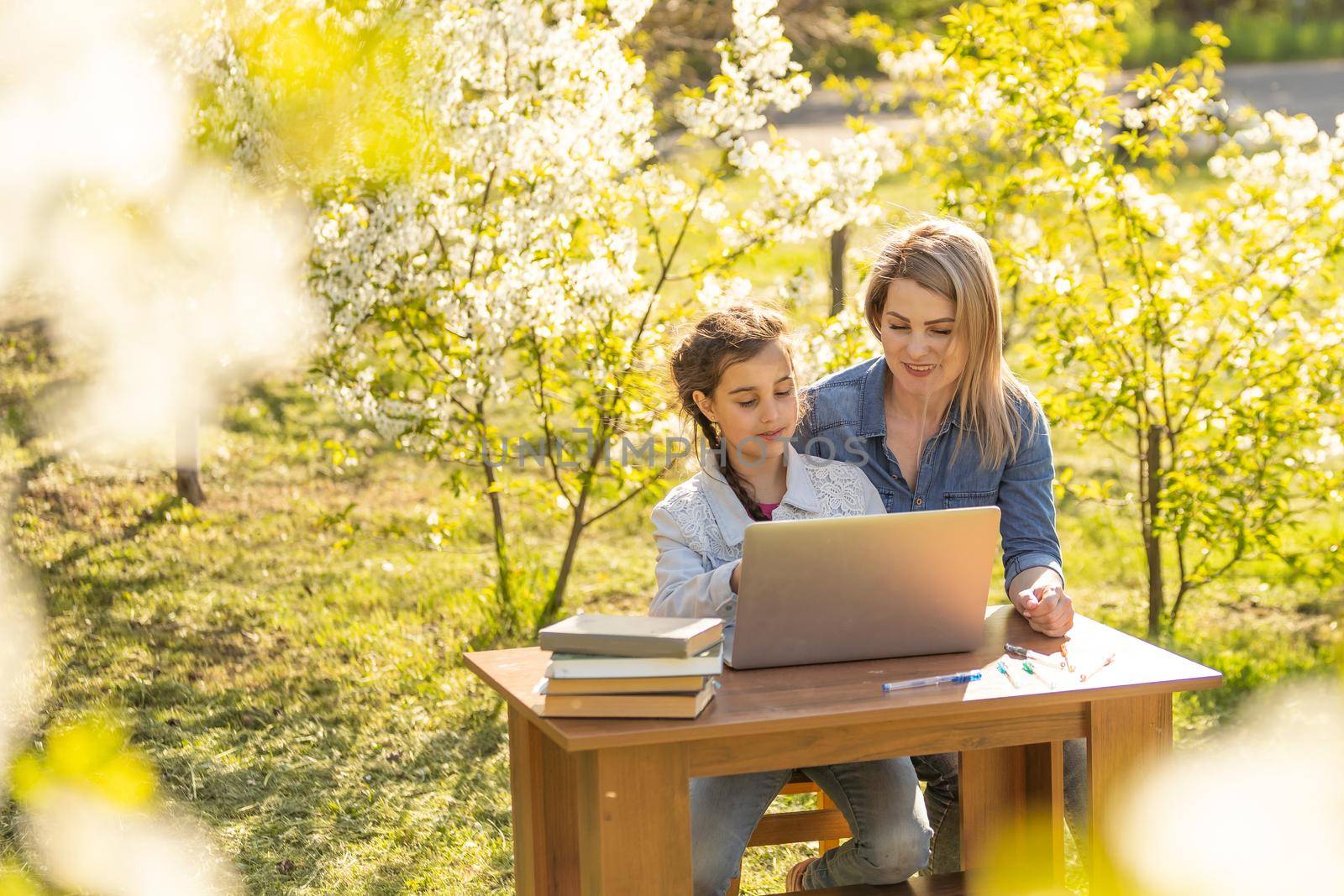 childhood, parenting and technology concept - happy mother with adorable little girl with laptop