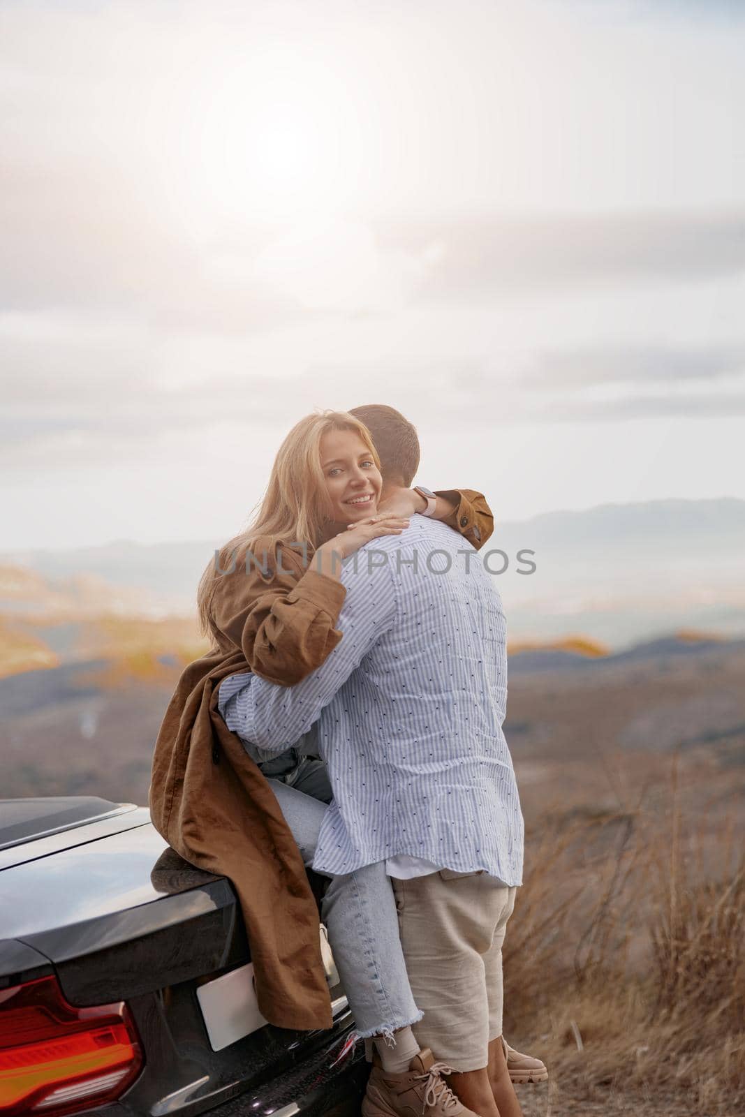 Vertical shot of pretty young blonde woman hugging her beloved husband outdoor. Love, family concept