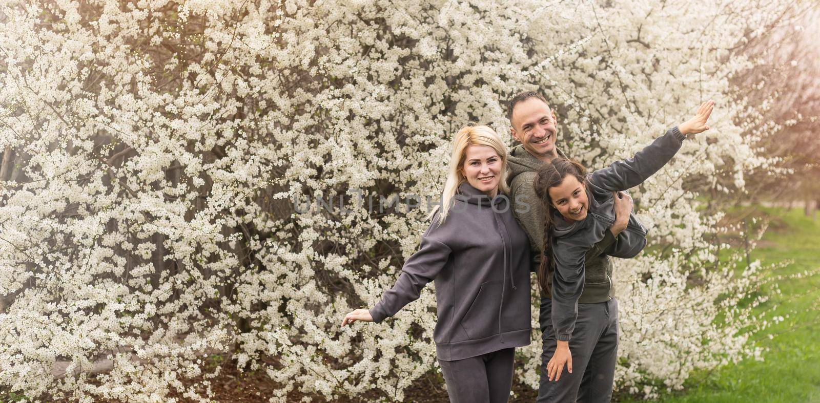 family having fun with flowering tree in blooming spring garden by Andelov13