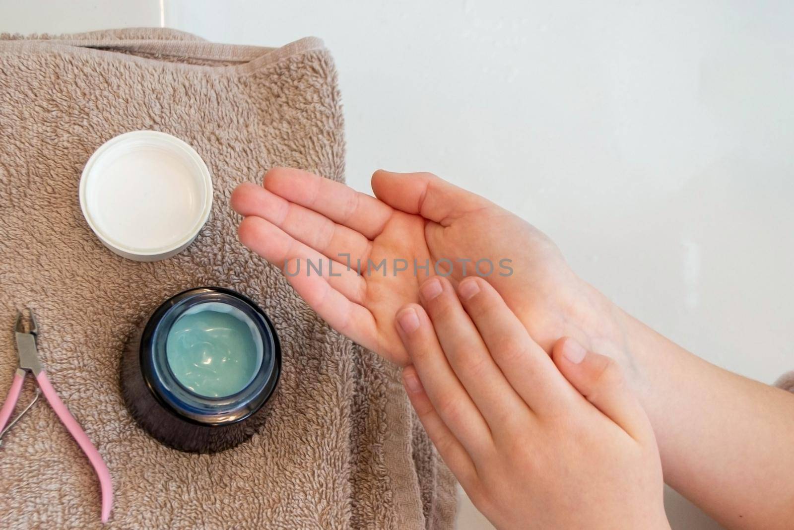 Close up horizontal photo of female index finger rubbing cosmetic cream onto other hand. High quality photo