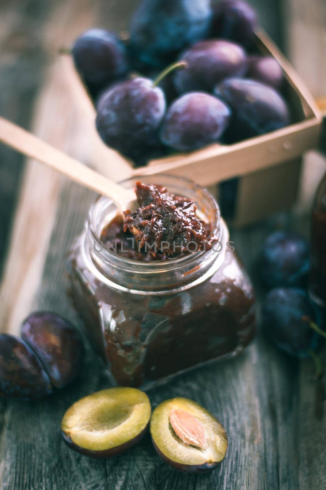 plum jam in glass jar with spoon on wooden background. High quality photo