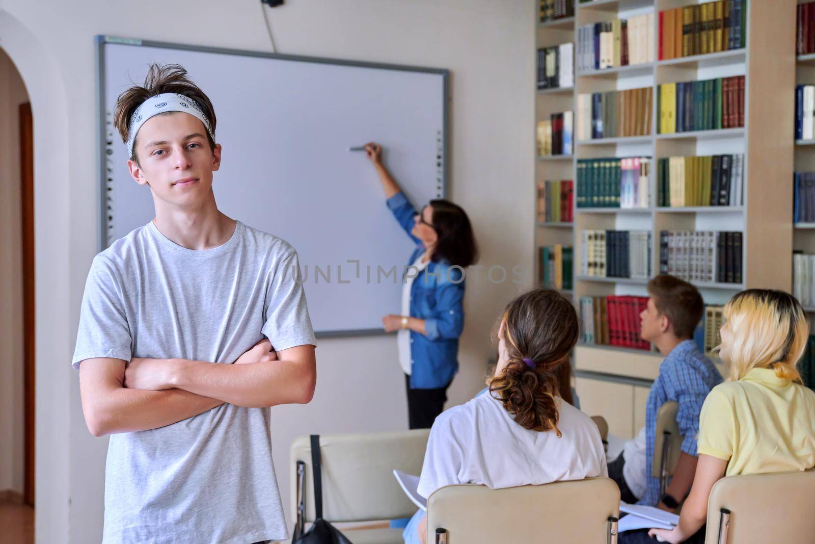Teenage guy in the classroom looking at the camera by VH-studio