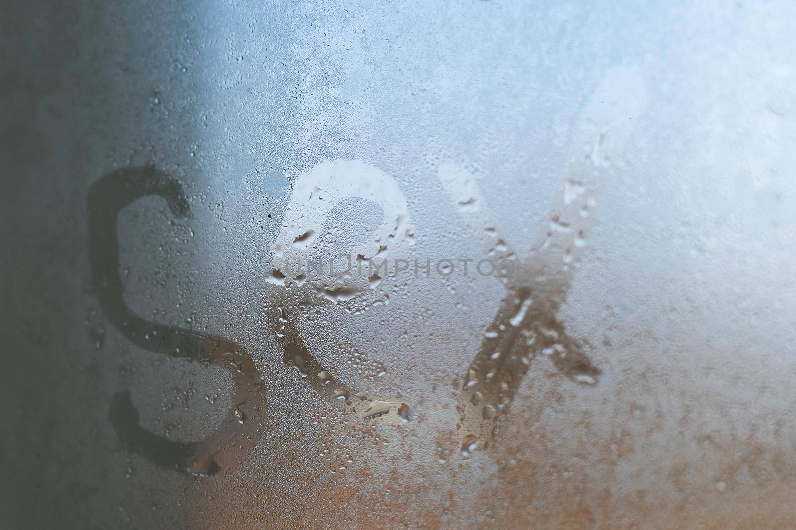 Sex inscription on the sweaty glass with drops dripping condensate. Concept photo of sex in the bathroom.