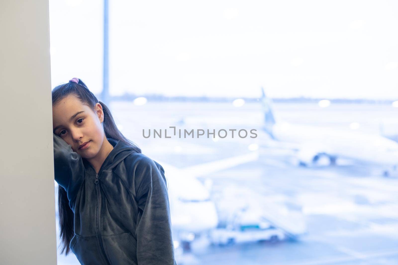 little baby girl waiting boarding to her flight in airport transit hall and looking at airplane parking near departure gate. Travelling by air with child.