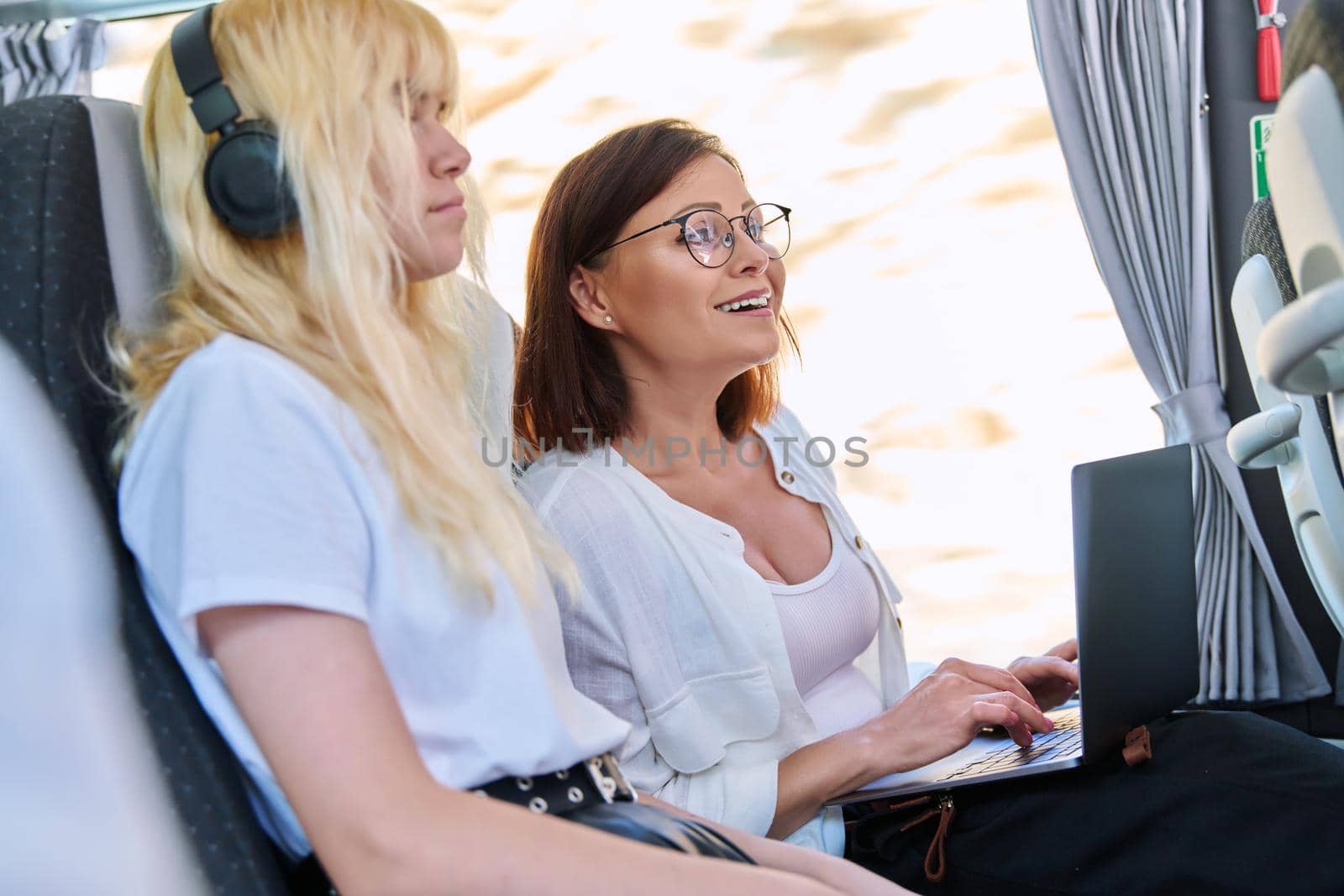Middle-aged woman in bus using laptop. Female on bus ride working on laptop. Lifestyle, technology, travel, freelance, remote work study concept