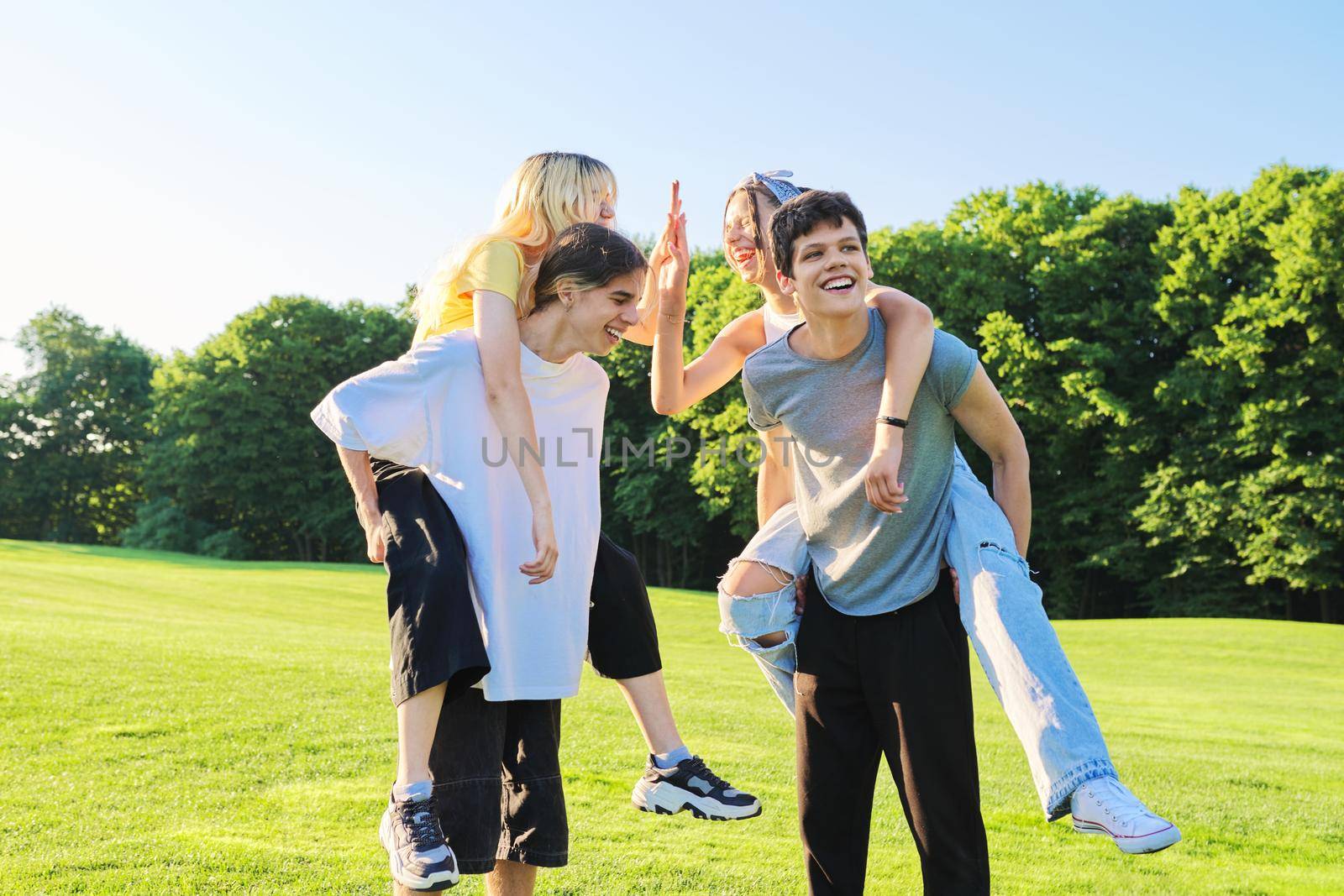 Teenage youth having fun in the park, happy laughing friends. Group of teenagers together on sunny day. Friendship, adolescence, summer, vacation, lifestyle, fun, happiness, holiday, leisure, people