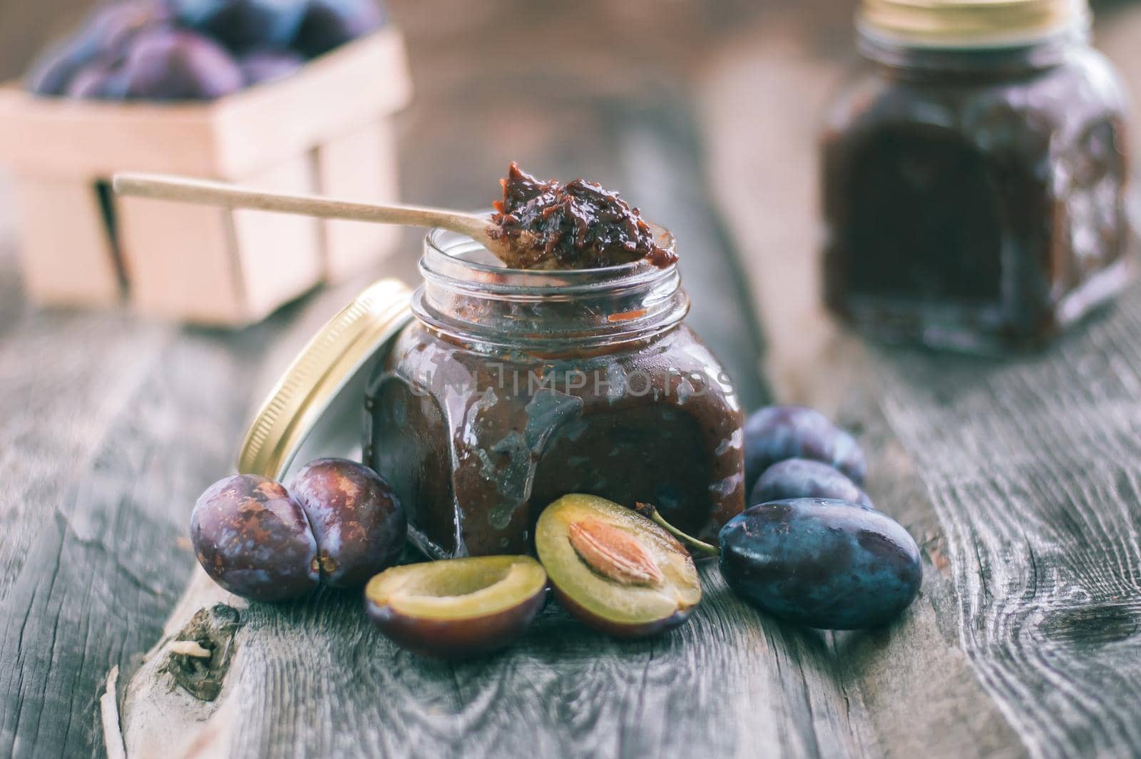 plum jam in glass jar with spoon on wooden background. High quality photo