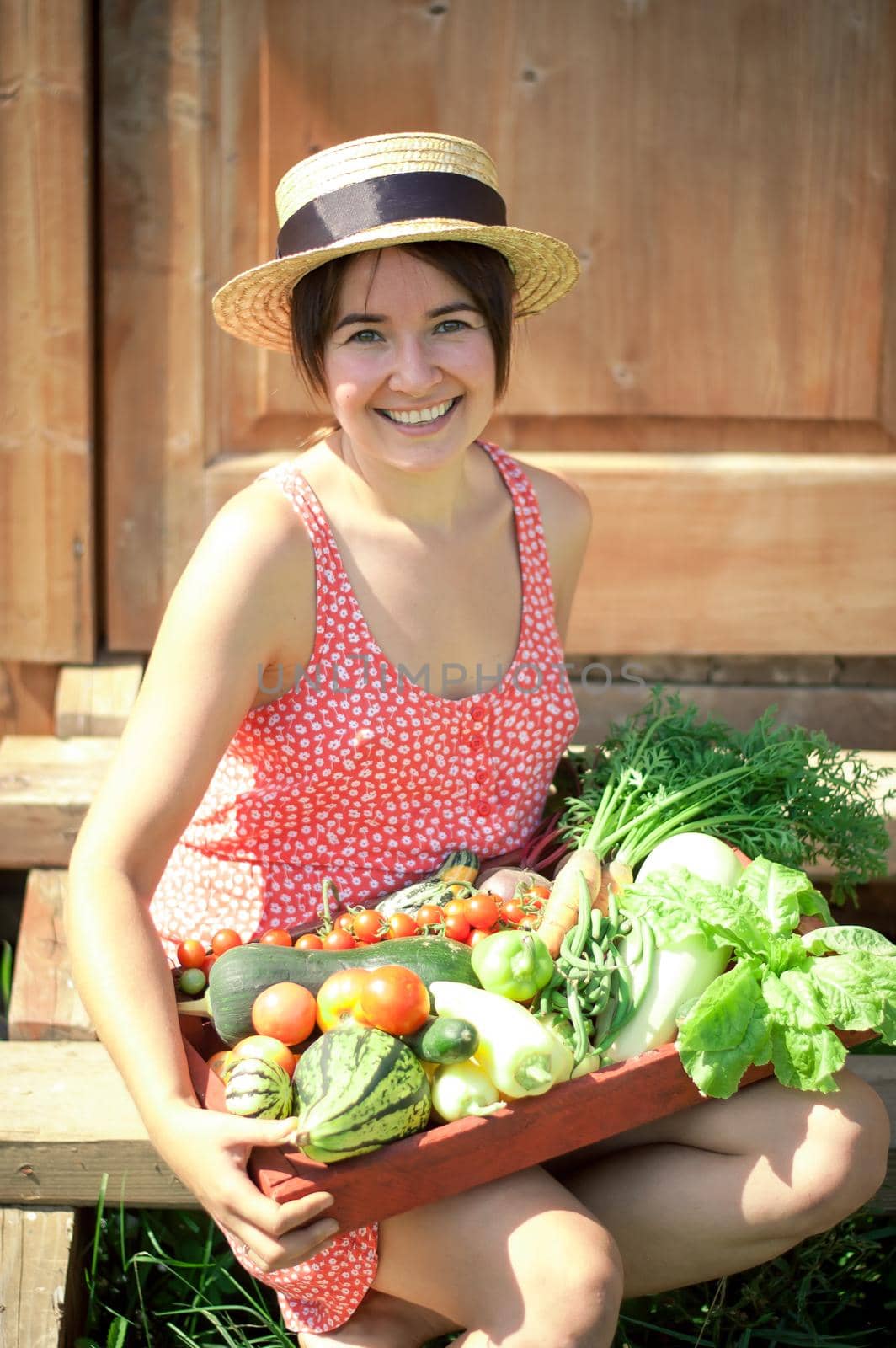 happy young girl holding harvest of vegetables next to wooden background. High quality photo