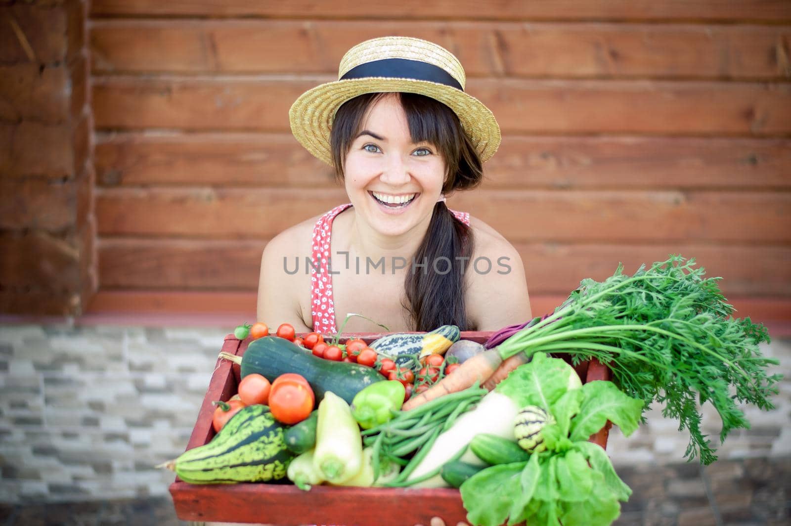 happy young girl holding harvest of vegetables next to wooden background. High quality photo