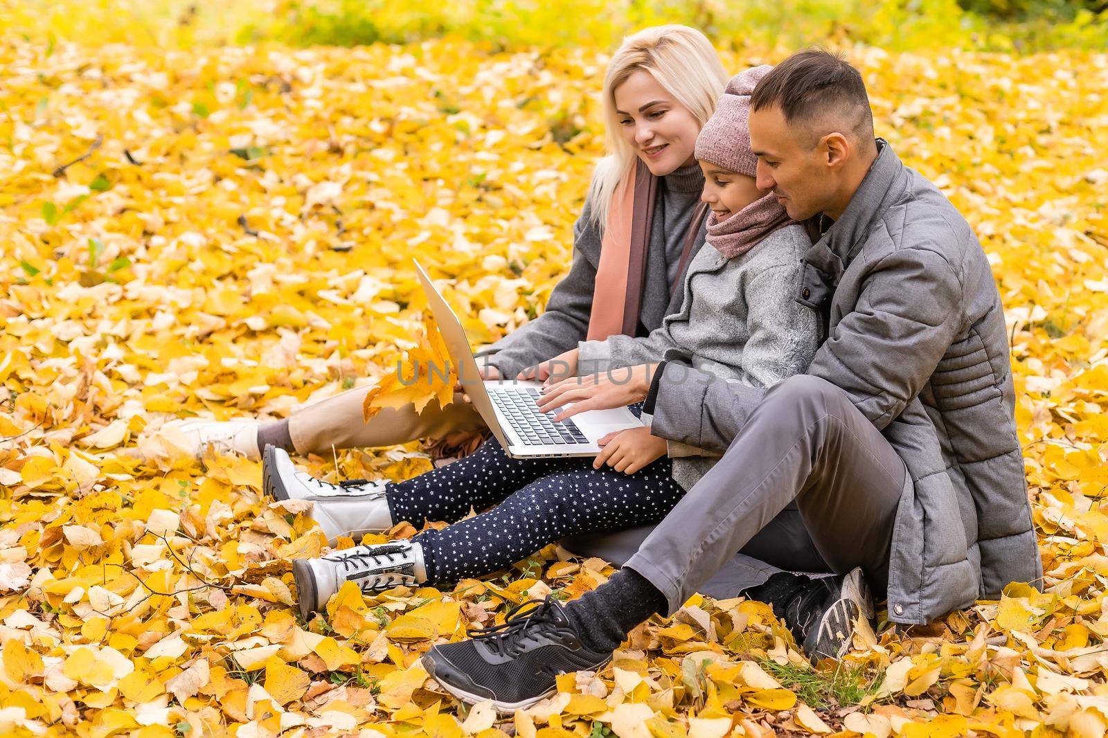 Family with laptop on an autumn day.