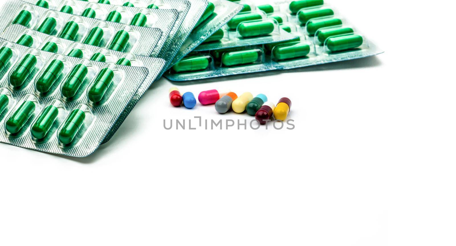 Green antibiotic capsule pill in blister pack and multicolored capsule pill on white background. Antibiotic drug resistance and prescription drugs concept. Pharmacy products. Pharmaceutical industry. 