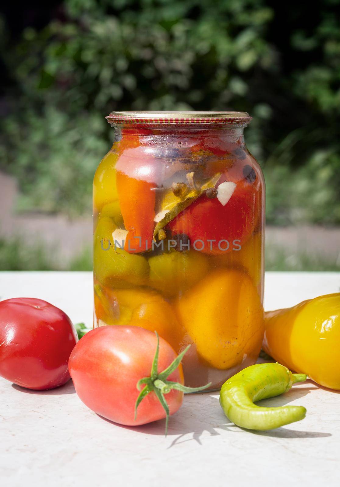 Glass jar with pickled peppers, covered with an airtight lid. The concept of preserving organic products. Front view, copy space.