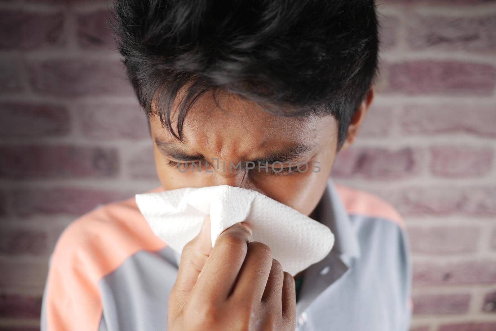 teenage boy with flu blow nose with napkin