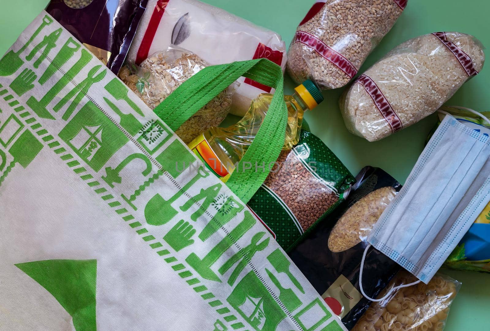 Crisis food supply for the period of quarantine isolation during the coronavirus pandemic. A set of products in a paper bag: rice, pasta, oatmeal, sugar, cereals. Food delivery. Top view, copy space
