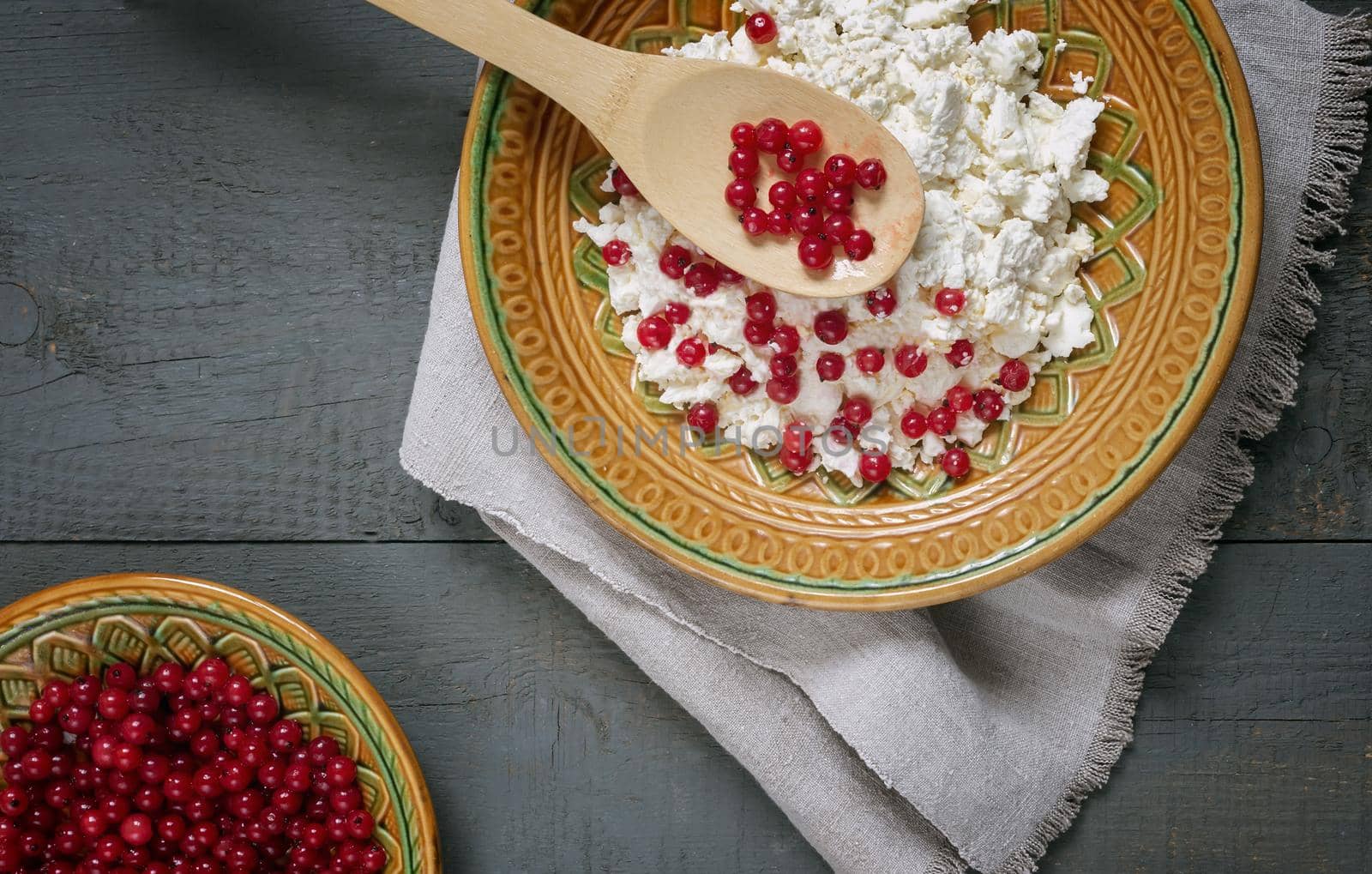 On the table in a ceramic plate delicious natural cottage cheese with red currant berries. close-up, top view. Copy space.
