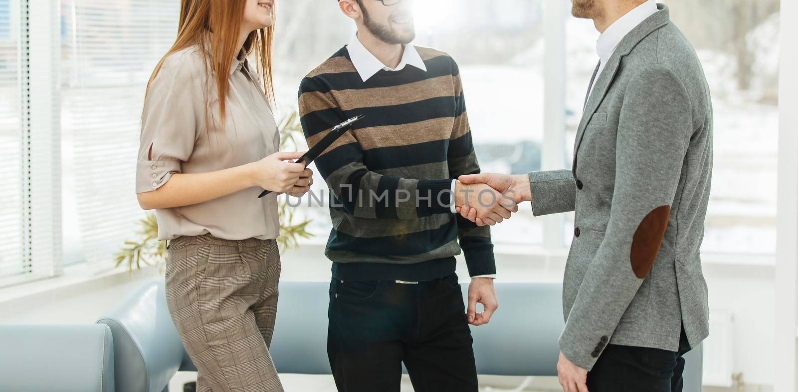 Manager shakes hands with the employee in a workplace in a modern office by SmartPhotoLab