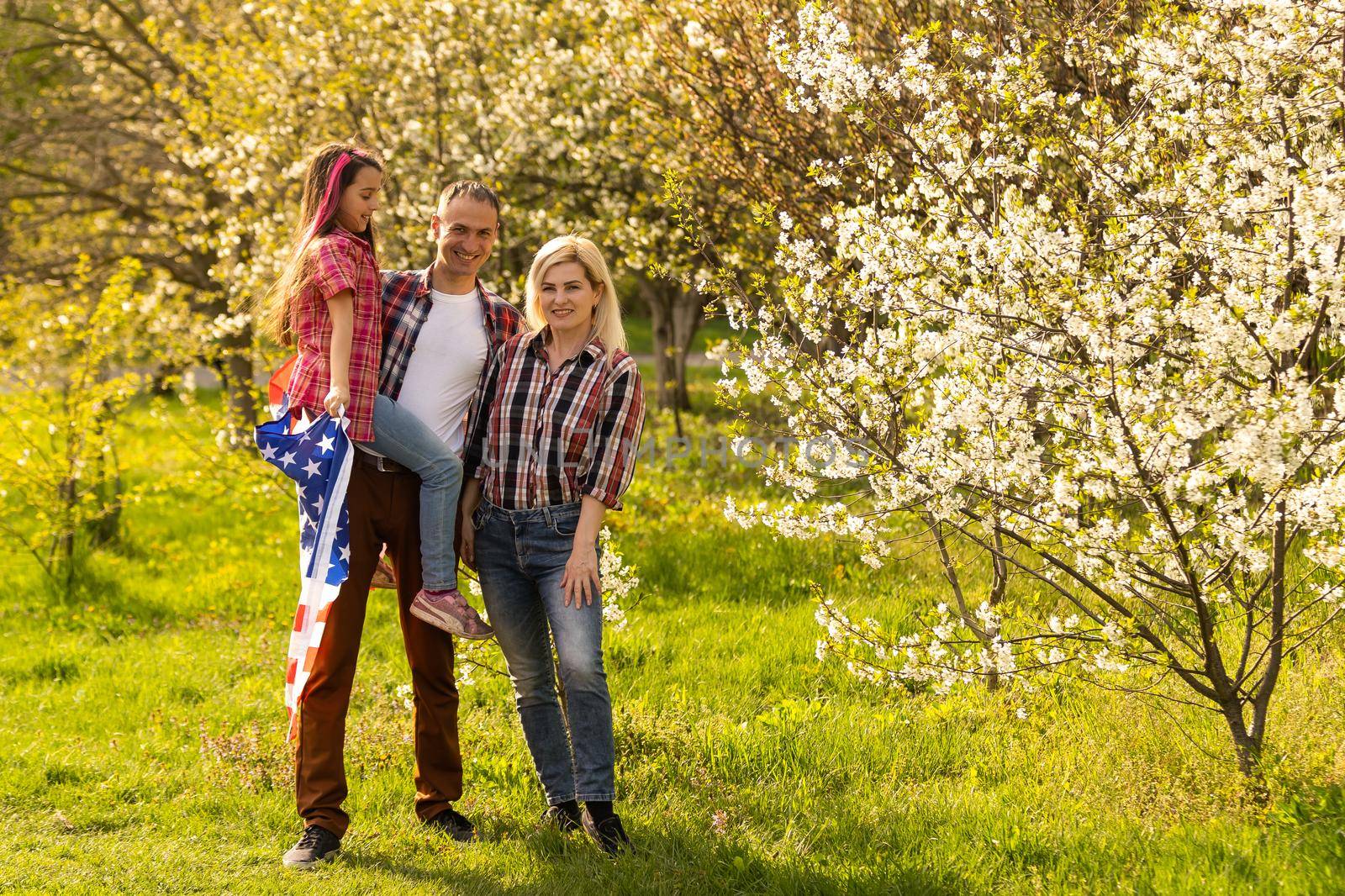 portrait of beautiful modern american family with USA flag outdoors