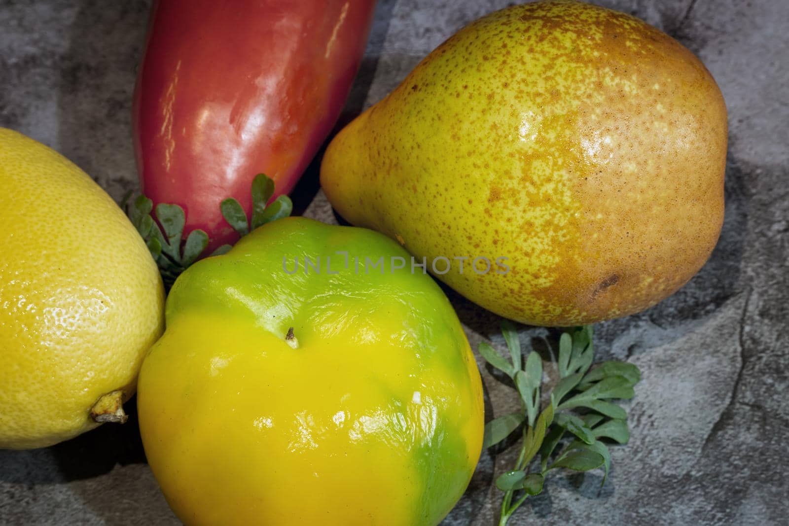 On the table on a napkin are ripe fruits: lemon, tangerine, pear and bulgarian red pepper. Top view, close-up.