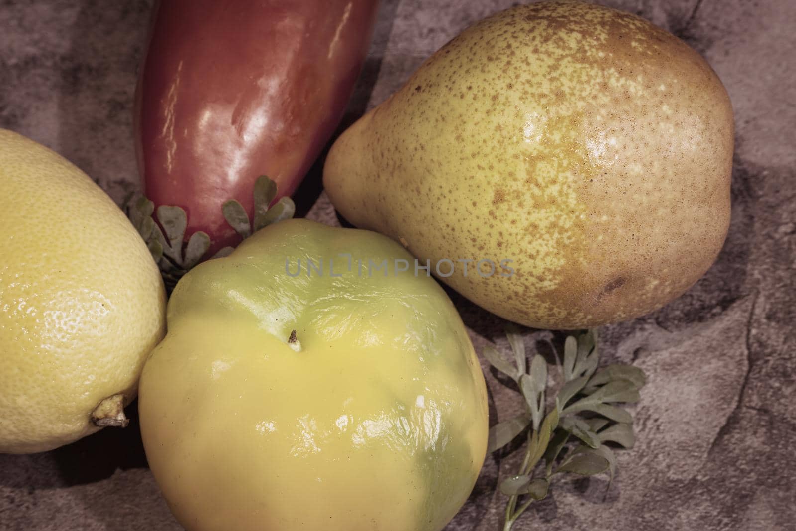 On the table on a napkin are ripe fruits: lemon, tangerine, pear and bulgarian red pepper. Top view, close-up.