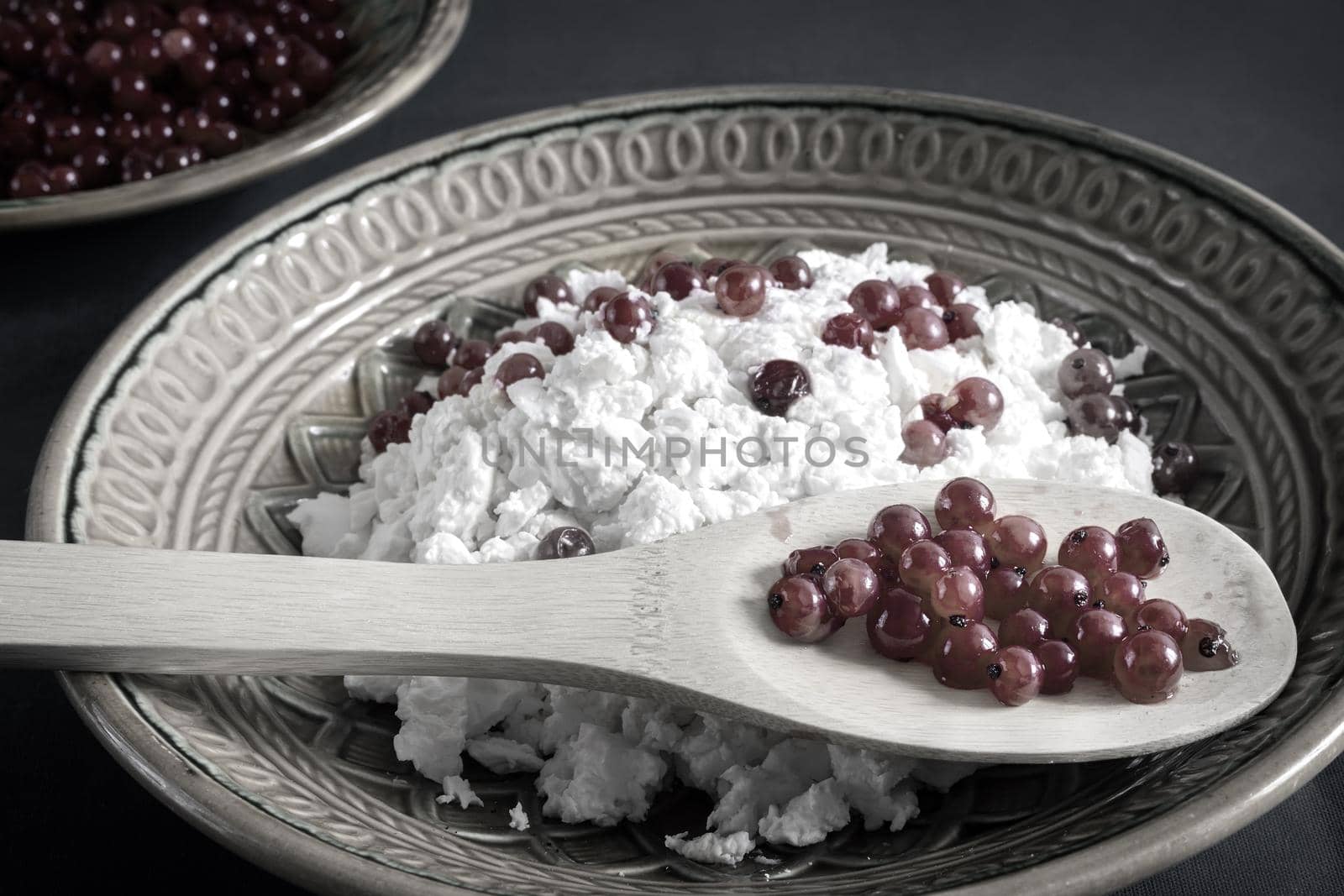 On the table in a ceramic plate delicious natural cottage cheese with red currant berries. Close-up, front view