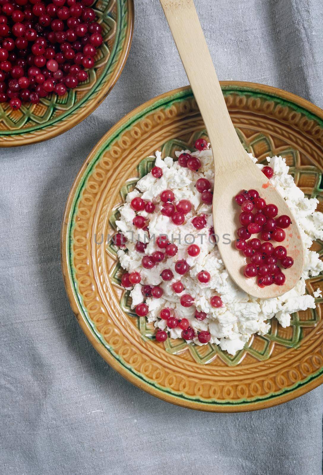 On the table in a ceramic plate delicious natural cottage cheese with red currant berries. close-up, top view.