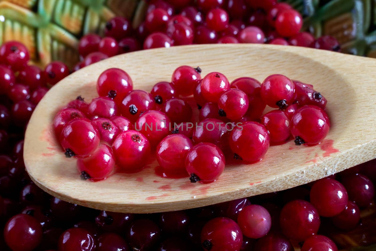 Wooden spoon with juicy and delicious red currant berries. Close up.